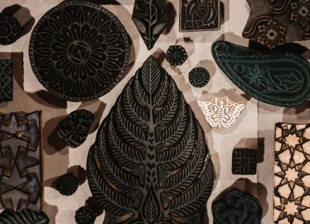 Uz galda izvietoti dažādu formu un rakstu koka spiedogi tekstila apdrukai.