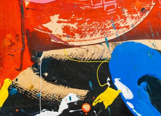 Abstrakta glezna ar spilgtiem krāsu laukumiem – dominē sarkans, zils, dzeltens un melns tonis, radot dinamisku kompozīciju ar šļakatām un krāsas notecējumiem.