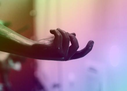 Skulptūras rokas fragments ar atplestu plaukstu daudzkrāsainā apgaismojumā.