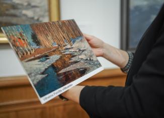 Persona tur rokās reljefa attēlu ar Vilhelma Purvīša gleznu “Atkusnis”, kas paredzēts taustes uztverei muzeja pieejamības programmas ietvaros.